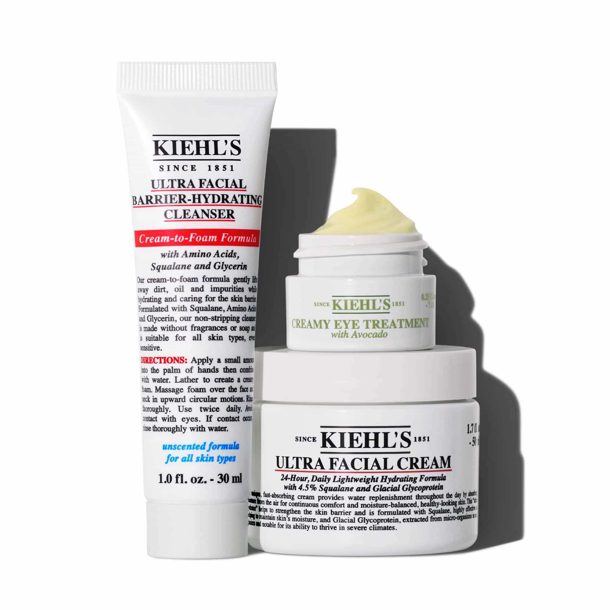 Grafika zobrazujici tři bile produkty Kiehl's vrhajici stin na bile pozadi: tubu "KIEHL'S ULTRA FACIAL BARRIER-HYDRATING CLEANSER", malou skleničku "KIEHL'S CREAMY EYE TREATMENT WITH AVOCADO" s viditelnym světle zelenym kremem a větši sklenici "KIEHL'S ULTRA FACIAL CREAM". Sklenice s očnim kremem a kremem na obličej jsou naskladane.