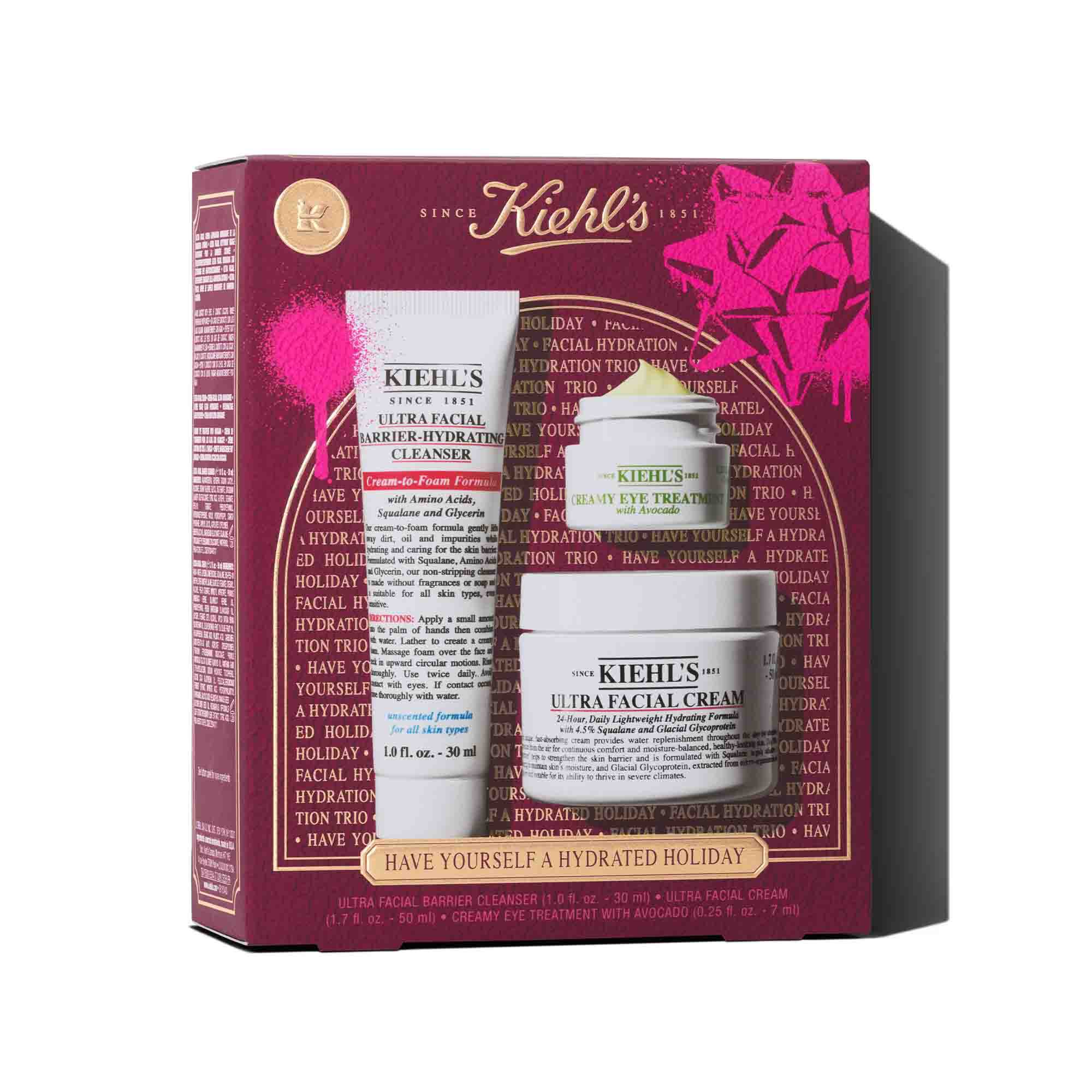 Grafika znazorňujici červenou darkovou krabičku Kiehl's. Krabička obsahuje tři produkty: bilou tubu "KIEHL'S ULTRA FACIAL BARRIER-HYDRATING CLEANSER", bilou nadobu "KIEHL'S CREAMY EYE TREATMENT WITH AVOCADO" s viditelnym světle zelenym kremem a bilou nadobu "KIEHL'S ULTRA FACIAL CREAM". Krabička je zdobena jasně růžovymi grafickymi cakanci barvy a vzorem mašle a ve spodni časti ma text "HAVE YOURSELF A HYDRATED HOLIDAY".