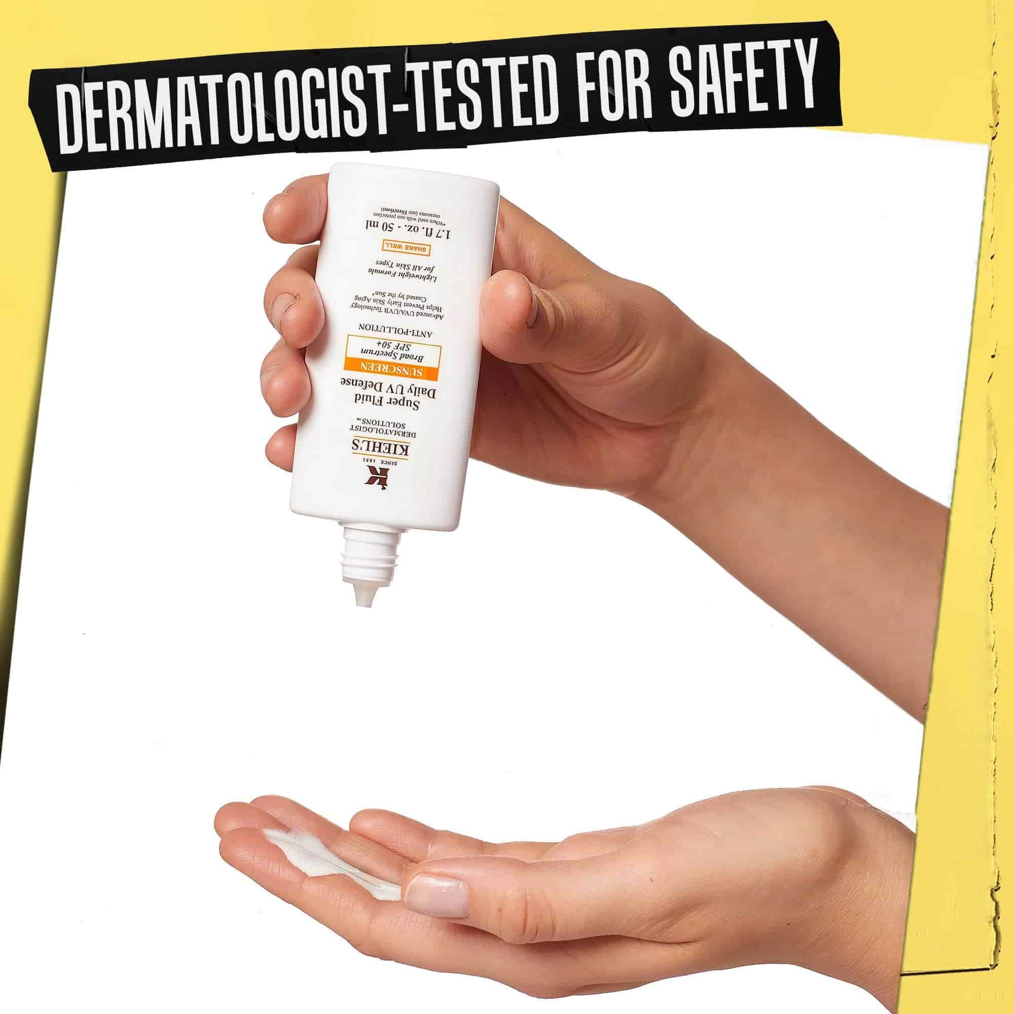 Ruka, na kterou se davkuje Ultra-Light Daily UV Defense, s napisem „Dermatologicky testovano pro bezpečnost“.