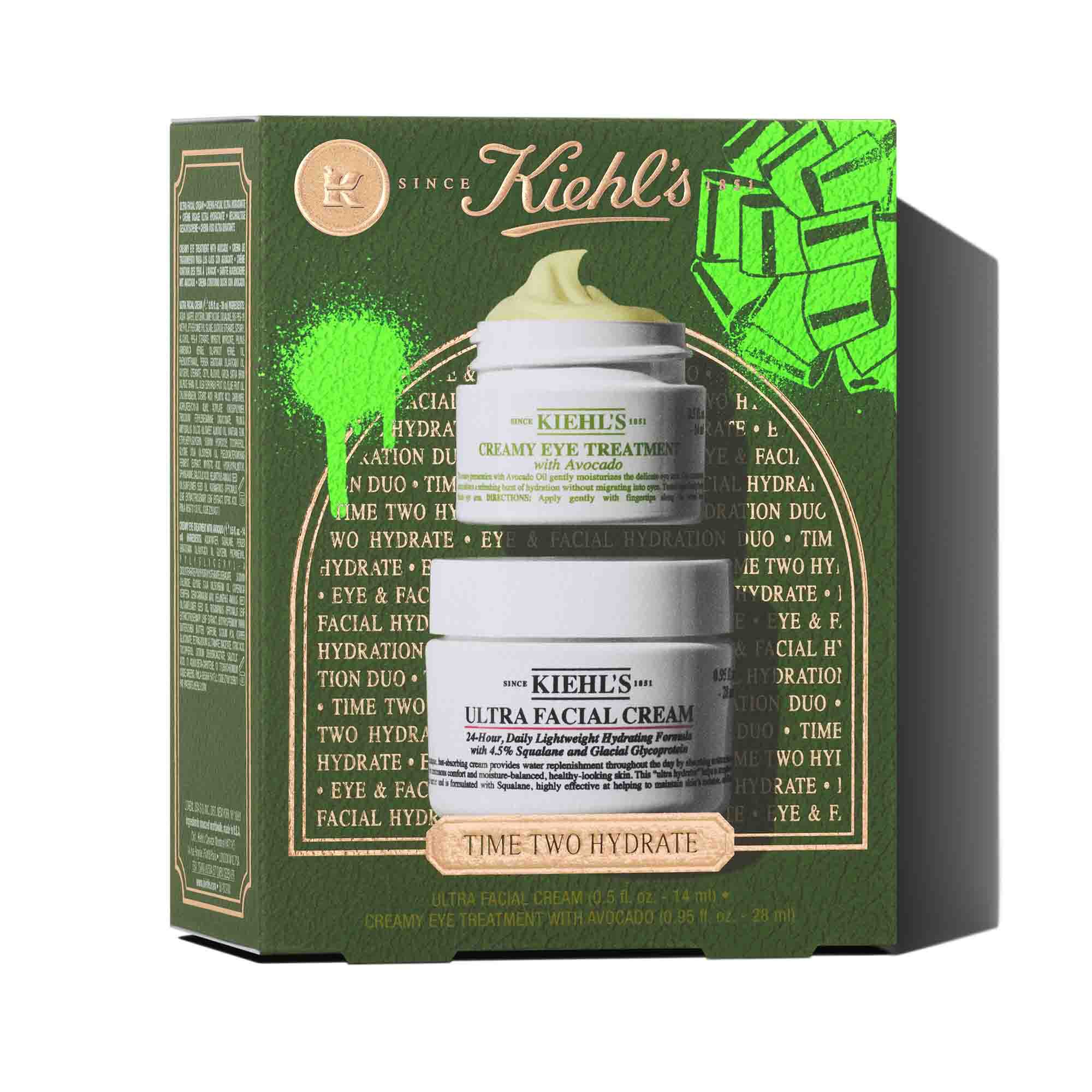 Dvě bile sklenice s produkty Kiehl's jsou naskladany svisle. Horni nadoba je "KIEHL'S CREAMY EYE TREATMENT with Avocado" zobrazujici žlutozeleny vir produktu nahoře. Spodni nadoba je "KIEHL'S ULTRA FACIAL CREAM". Obě sklenice vrhaji stiny na bile pozadi.