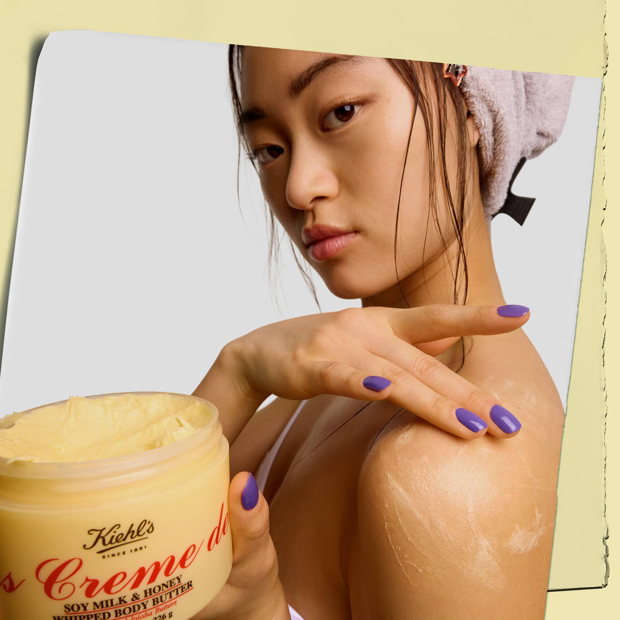 Modelka držici skleničku a nanašejici tělove maslo Kiehl's Creme de Corps Whipped Butter