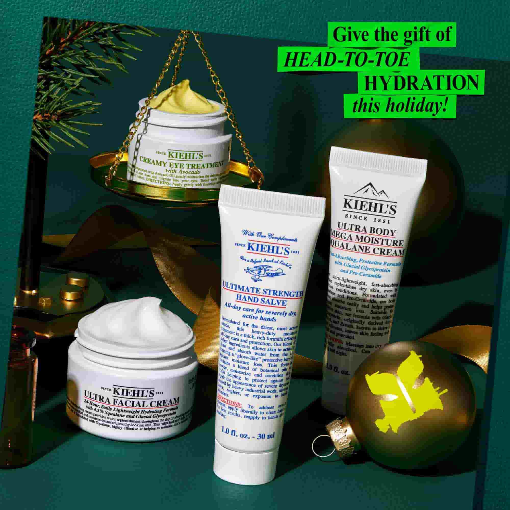 Grafika na tmavě zelenem texturovanem pozadi zobrazuje několik produktů a svatečnich dekoraci společnosti Kiehl's. Mala otevřena bila doza "KIEHL'S CREAMY EYE TREATMENT WITH AVOCADO" s viditelnou světle žlutou kremovou barvou je vyvažena na zlate vaze s borovicovou větvičkou. Na povrchu je take uspořadana bila nadoba "KIEHL'S ULTRA FACIAL CREAM" s viditelnym bilym kremem, bila tuba "KIEHL'S ULTIMATE STRENGTH HAND SALVE" a bila tuba "KIEHL'S ULTRA BODY MEGA MOISTURE SQUALANE CREAM". Současti slavnostniho představeni je zlaty kulovity ornament se zelenym logem "K" a tmavou stuhou. V pravem hornim rohu je jasně zeleny rameček s textem "Darujte o letošnich svatcich HYDRATACI OD HLAVY AŽ K PATĚ!"