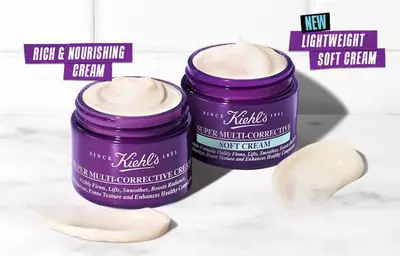 Two jars of Kiehl's Super Multi-Corrective Cream, one labeled "Rich & Nourishing Cream" and the other "New Lightweight Soft Cream," with a creamy texture swirled on the side.