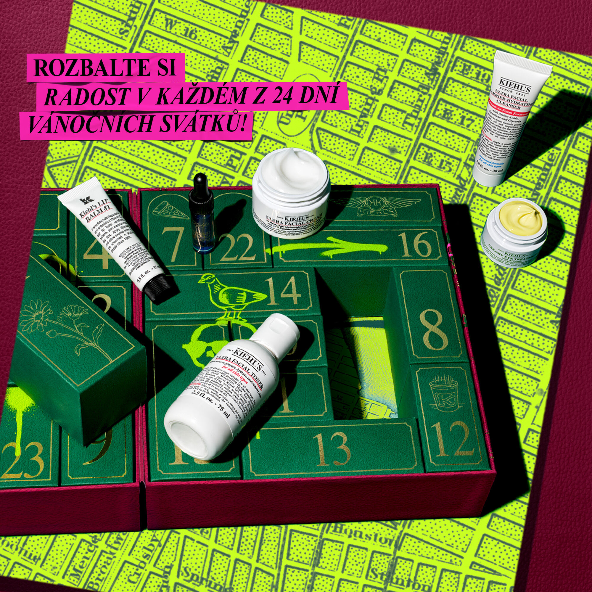 he left side features an open green Kiehl’s Advent Calendar with visible numbered compartments. Several Kiehl's skincare products are shown, some appearing to be removed from the calendar, including white tubes, dark jars, and a blue jar. Bright green graphic accents are seen on the calendar itself. The right side of the graphic is a solid purple background with white text that reads "HOLIDAY DROP: KIEHL'S ADVENT CALENDAR" and a smaller "SHOP NOW" below it.