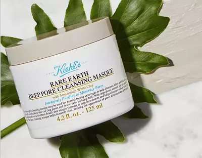 Bily kelimek na pleťovou masku Kiehl's s nazvem 'Rare Earth Deep Pore Cleansing Masque' na mramorovem povrchu.