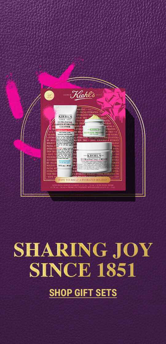 The left side features two Kiehl’s holiday gift sets. On the left is a maroon and pink gift box containing a tube of "KIEHL’S ULTRA FACIAL CLEANSER," a jar of "KIEHL’S CREAMY EYE TREATMENT WITH AVOCADO", and a jar of "KIEHL’S ULTRA FACIAL CREAM." On the right is a blue and green gift box containing a jar of "KIEHL’S ULTRA FACIAL CREAM" and a jar of "KIEHL’S ULTRA BODY MEGA MOISTURIZER SQUALANE CREAM." Both boxes have festive accents. The right side of the graphic is a solid purple background with white text that reads "SET-SATIONAL GIFTS TO GIVE" and a smaller "GET SET" below it.
