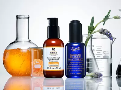 Skleněne nadoby s kosmetickymi produkty Kiehl's, zaměřene na pleť, obklopene pomerančovym serem a levanduli.