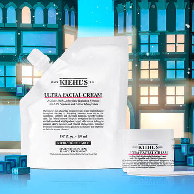 A pouch of Kiehl's Ultra Facial Cream alongside a small jar of the same product, set against a festive background with stylized buildings and snowflakes.