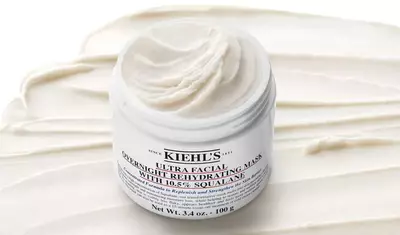 A jar of Kiehl's Ultra Facial Overnight Rehydrating Mask, with a creamy texture and a smooth, white backdrop. The jar is labeled prominently and showcases its contents.