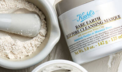 A container of Kiehl's Rare Earth Deep Pore Cleansing Masque, showcasing the product's light gray clay in a bowl alongside a pestle. The label highlights the product's purpose of purifying and minimizing pores.