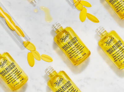 Sada lahviček s olejem Kiehl's Daily Reviving Concentrate na mramorovem pozadi s okvětnimi listky.