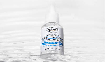 A clear glass bottle of Kiehl's Ultra Pure High-Potency Serum with a white label, featuring blue text and a dropper cap, set against a soft, blurred background.