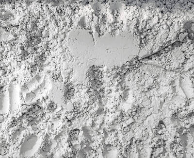 A textured surface of grayish-white powder with a rough appearance, resembling fine dust or mineral particles.