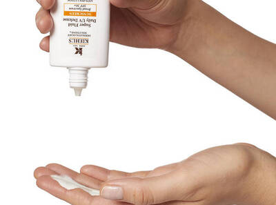 Ruka držici produkt Kiehl's, nanašejici krem na zapěsti.