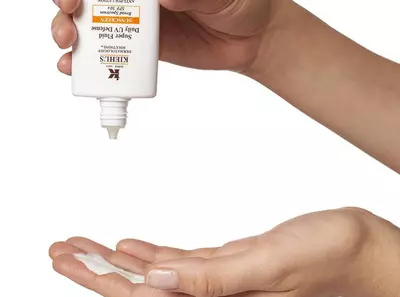 Ruka držici produkt Kiehl's, nanašejici krem na zapěsti.